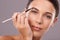 Accentuating her beautiful eyes. Studio shot of a woman applying makeup to her eyebrow.