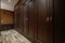 Access hallway to the dressing room with access to numerous built-in wardrobes with brown wooden doors, a radiator cover