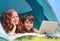 Accessing the web from the wilderness. A young brother and sister surfing the web while out camping.