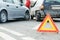 Accident or crash with two automobile. Road warning triangle sign in focus