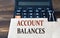 ACCOUNT BALANCES - words on light brown paper on calculator background