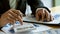 At the accounting desk, an accountant presses a calculator to analyze investment charts to generate monthly financial reports or c