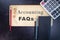 Accounting FAQs wooden sign with office tools and supplies