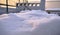 Accumulation of snow on the table outside with blurred chimneys