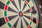 Accurate dart sight hitting center of target, dartboard and dart, blurred background