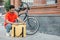 Accurate delivery. Busy bearded courier zips up large yellow bag, beside a bicycle