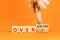 Achiever or overachiever symbol. Businessman turns wooden cubes and changes word Achiever to Overachiever. Beautiful orange