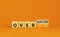 Achiever or overachiever symbol. Businessman turns wooden cubes and changes word Achiever to Overachiever. Beautiful orange