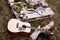 Acoustic guitar on the grass and flowers, a tree branch and candles on a wooden stand.