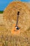 Acoustic guitar laying near a bail of hay