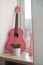 Acoustic guitar stands on a windowsill