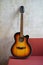 Acoustic vintage black and orange guitar on red couch at loft style apartment over concrete wall