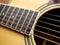 Acoustic wood guitar close up on wooden background with fretboard, strings, and tuners for music blogs, website banners.