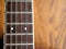 Acoustic wood guitar close up on wooden background with fretboard, strings, and tuners for music blogs, website banners.