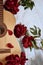 An acoustic wooden guitar lies on a white sheet surrounded by red peonies