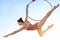 Acrobat athletic, young graceful gymnast performing aerial exercise in the air ring outdoors on sky background at sunset. flexible