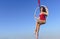 Acrobat athletic, young graceful gymnast portrait on aerial ring outdoors on sky background. flexible woman in red suit performs