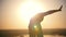 Acrobat makes wheel back, setting sun, slow-motion
