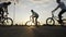 Acrobat young bikers squad doing ollie hop tricks on bikes with summer sunset in background