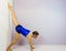 Acrobatic gymnastics stretching against a wall to work toward the wall split or needle preformed by a young transgender girl