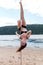 Acrobatic performance laughing brunette woman in swimsuit on pole for dancing