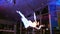 Acrobatic show, flexible girl balances on gymnastic hoop in air at evening event