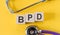 Acronym for BPD (Borderline Personality Disorder)  built from blocks of wood on a yellow table with a stethoscope