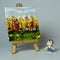 Acrylic landscape painting on mini canvas on easel stand with a miniature of little boy standing beside