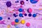 Acrylic paint balls abstract texture. Purple, blue, pink and yellow liquids mix. Creative multicolor background. Bright