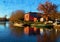 Acrylic painting of a fisherman`s house on the river Havel. Boats are reflected in the water. Autumn