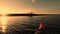 Action camera films kayaking in calm water. Silhouettes of small island with few trees, forest on coastline and beautiful golden