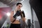 Action lifestyle portrait of a beautiful female athlete exercising and training in a gym, sweaty, holding fists up ready to attack
