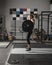 Action shot of female power lifter doing clean and jerk with heavy weights in gym