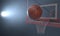 An action shot of a regular basketball teetering on the rim of a red basketball hoop