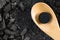 Activated carbon pill medicine in wooden spoon on ground charcoal