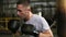 Active, angry male boxer training process in gym. Portrait of a man boxing using punching bag, practicing kicks at