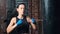 Active Asian fitness woman in sportswear enjoying kickboxing hitting punching bag slow motion