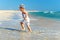 Active baby boy having fun in surf on the beach