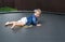 Active barefoot baby girl plays outdoors in playground. Portrait of the little girl on a trampoline