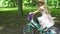 Active beautiful blond girl ride fast her bicycle in tree alley. Gimbal follow