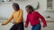 Active black teenage girls dancing in domestic kitchen