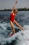 Active blonde woman wakesurfer riding down the blue splashing wa