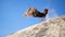 Active boy jumping from sand hill, slow motion