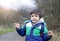 Active boy pointing wooden stick up  while walking in forest park,Child boy having fun playing outdoor activity,Preschool Kid wear