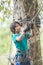 Active brave boy enjoying outbound climbing at adventure park on