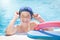 Active child (boy) in cap, sport goggles ready to learns professional swimming with pool board and swim noodles.