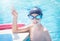 Active child (boy) learns professional swimming and doing victory sign in summer day.