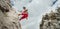 Active climber middle age man in protective helmet looking at camera while abseiling from cliff rock wall using rope with belay