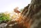 Active climber woman in protective helmet abseiling from cliff rock wall using rope with belay device and climbing harness. Active