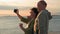 active couple on vacation, charming male and female pensioners take a selfie on a smartphone while walking along sea